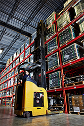 Side image of a forklift bringing down an item from a warehouse